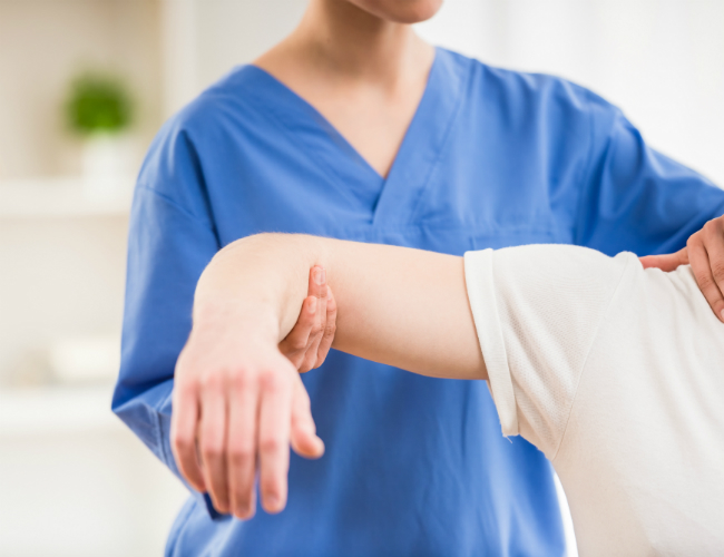 A doctor holding a person's right shoulder and arm during diagnosis
